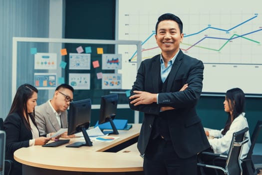 Successful businessman standing with arms crossed with confident. Intellectual. looking at camera. serious professional managers discussing about investment behind. conference room. Intellectual.