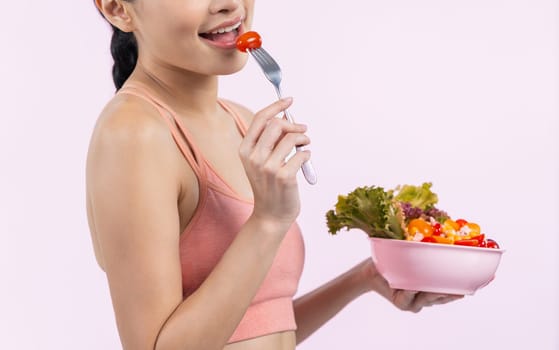 Young sporty Asian woman in sportswear holding salad bowl fill with vibrant of fruit and vegetable. Natural youthful and fit body lifestyle with balance nutrition on isolated background. Vigorous