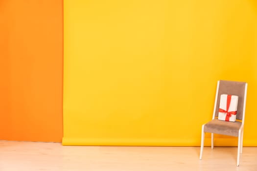 chair with gift in interior on yellow background