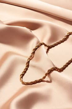 Golden chain necklace on silk background close up photo