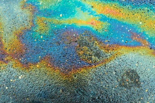 Colored oil stains close up, the color of the gasoline stain on the pavement road as a texture or background.