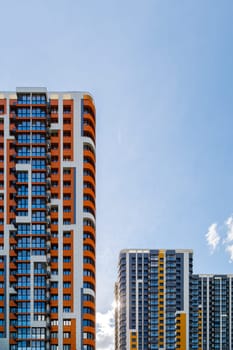 freshly built high rise apartment buildings on blue sky background with white clouds.
