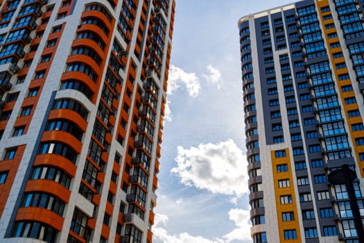 freshly built high rise apartment buildings on blue sky background with white clouds.