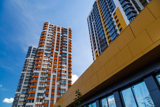 freshly built high rise apartment buildings on blue sky background with white clouds.