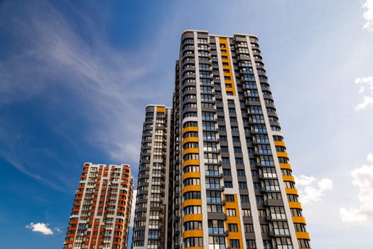 freshly built high rise apartment buildings on blue sky background with white clouds.
