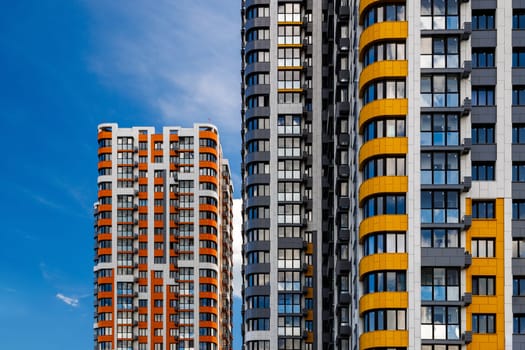 freshly built high rise apartment buildings on blue sky background with white clouds.