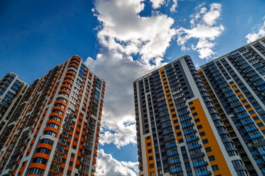 freshly built high rise apartment buildings on blue sky background with white clouds.