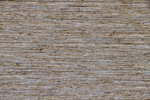 full-frame background and flat texture of stack of OSB compressed sawdust sheets.