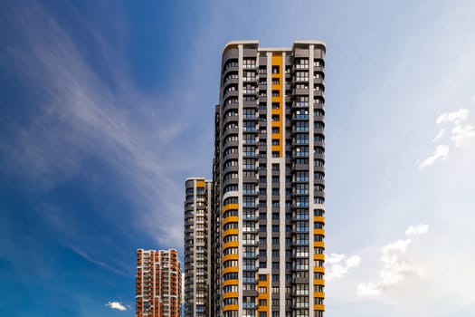 freshly built high rise apartment buildings on blue sky background with white clouds.