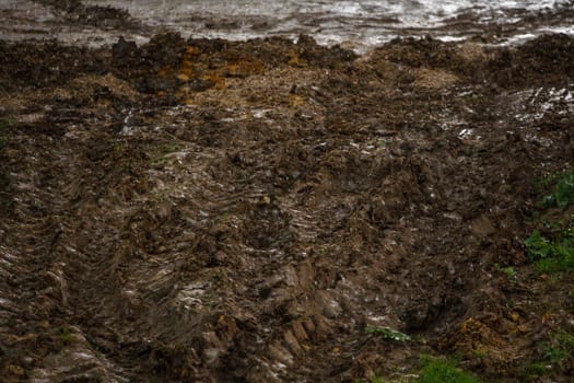 heavy vehicle tracks on dirt surface under summer rain at day light, season of bad roads