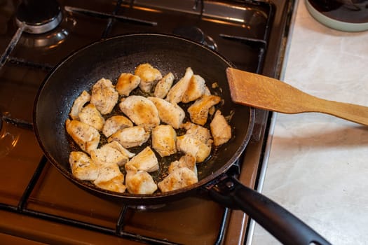 chicken breasts meat only on frying pan and wooden spatula, domestic healthy cuisine in real life situation.