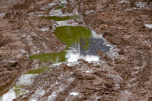 puddle in dirt road at summer day, closeup with selective focus.