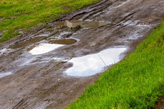puddle in dirt road at summer day, closeup with selective focus.