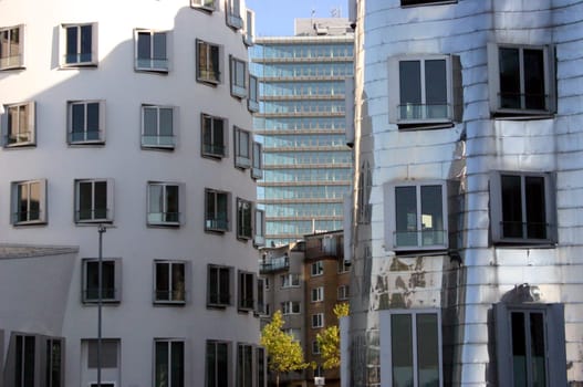 Houses by the architect Frank O. Gehry in Düsseldorf's Medienhafen,with some old buildings and another high-rise building in between in the background.
