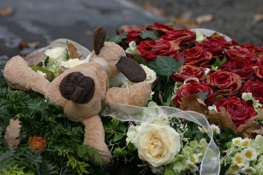Plush toy and roses on a fresh children's grave