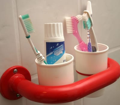 White toothbrush cups in red holder with toothbrushes