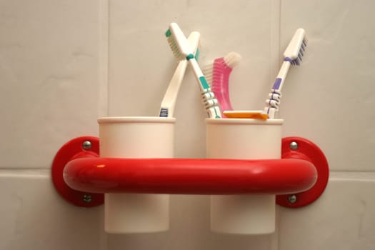 White toothbrush cups in red holder with toothbrushes