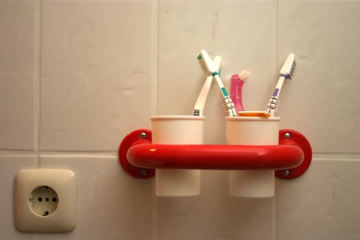 White toothbrush cups in red holder with toothbrushes