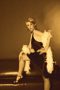 A woman stands with one leg on the sofa and looks directly into the camera.