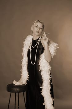 A woman dressed in the style of the 20s stands next to a bar stool with a cigarette.