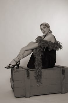 A woman dressed in the style of the 20s sits relaxed on an ammunition box