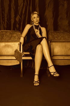 A woman dressed in the style of the 20s sits seriously in the cinema