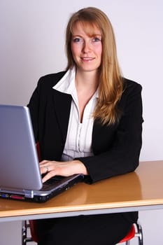 The picture shows a secretary sitting at the computer and smiling at the camera.