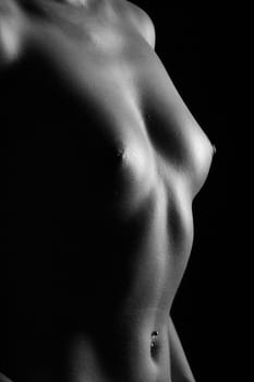 Low-key shot of a standing woman,visible chest and abdomen,shot in black and white