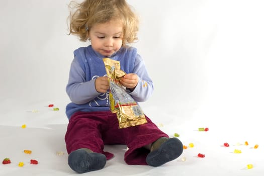 Child with a bag of Haribo and surrounded by gummy bears