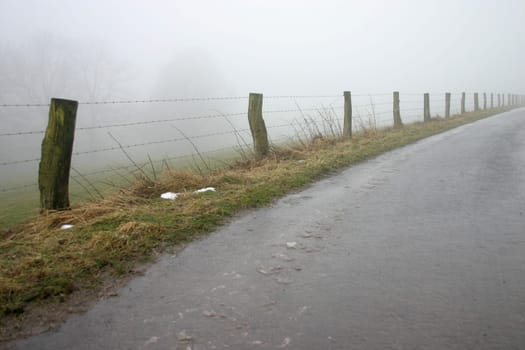 Pasture fence and road in the fog