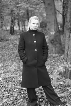A woman stands in the forest and looks grimly into the camera