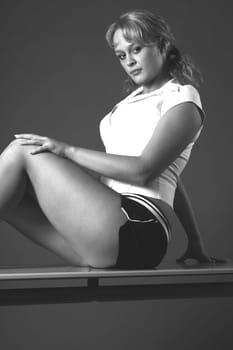 Woman sitting on desk in sports dress,smiling