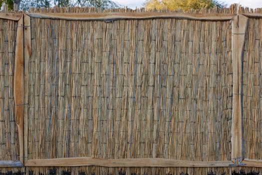 rustic fence made of wicker straw mat.