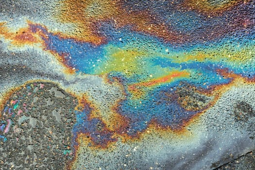Colored oil stains close up, the color of the gasoline stain on the pavement road as a texture or background.