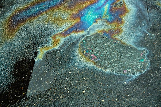 Colored oil stains close up, the color of the gasoline stain on the pavement road as a texture or background.