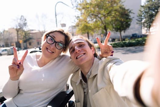 selfie of a couple of a man and woman using wheelchair smiling happy, concept of friendship and social media