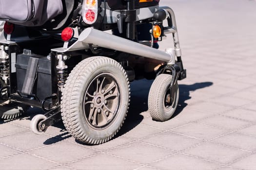 cropped photo of an electric wheelchair on a sidewalk, concept of urban mobility for people with disability, copy space for text
