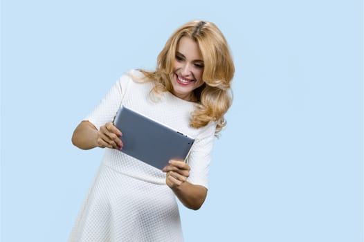 Portrait of happy mature woman using digital tablet. Isolated on pale blue.