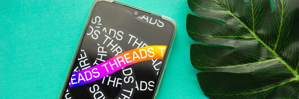 Tver, Russia - July 15, 2023, threads logo on the smartphone screen, on a green background. The threads icon. The logo of the current application. Threads social network