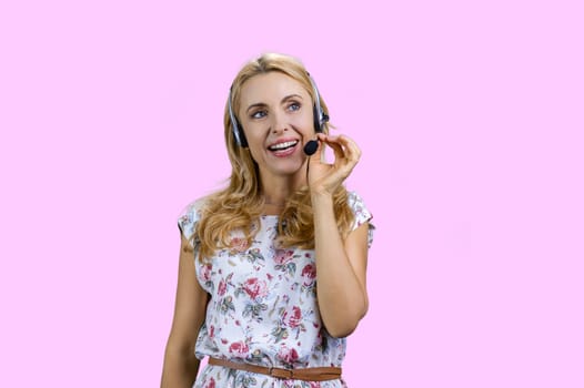 Portrait of happy cheerful blonde woman wearing headset. Isolated on pink.