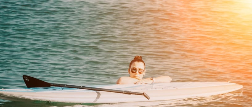 Sea woman sup. Silhouette of happy middle aged woman in rainbow bikini, surfing on SUP board, confident paddling through water surface. Idyllic sunset. Active lifestyle at sea or river