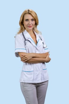 Vertical shot of attractive female doctor with folded arms. Isolated on blue.