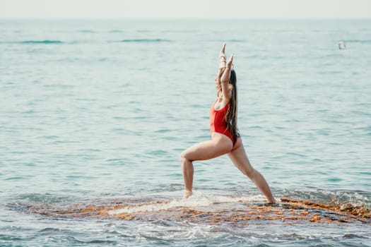 Woman sea yoga. Back view of free calm happy satisfied woman with long hair standing on top rock with yoga position against of sky by the sea. Healthy lifestyle outdoors in nature, fitness concept.