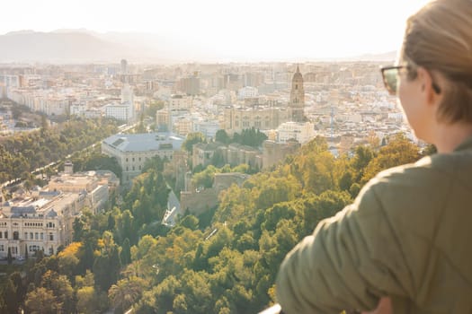 Bolnde female touris enjoying amazing panoramic aerial view of Malaga city historic center, Coste del Sol, Andalucia, Spain.