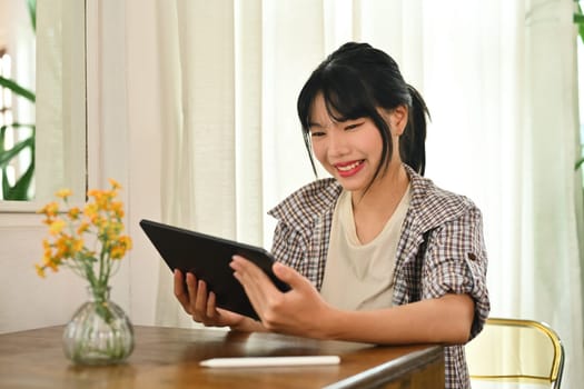 Carefree young asian woman using digital tablet, surfing internet or watching video. People, technology and lifestyle.