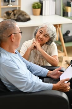 Loving senior couple having a conversation together while relaxing in cozy home. Elderly lifestyle and marriage concept.