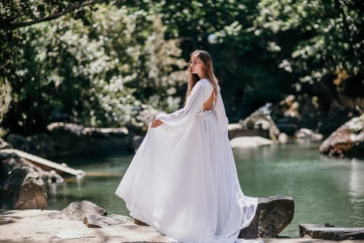 a beautiful woman in a long white dress looks into the distance at a beautiful lake with swans