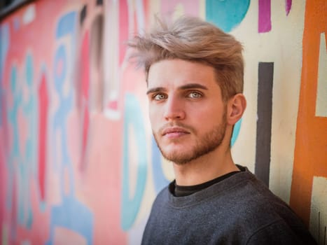 A man standing in front of a colorful wall. Photo of a man standing in front of a vibrant and colorful wall