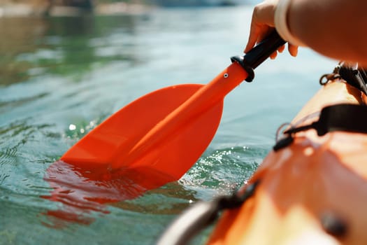 Kayak paddle sea vacation. Person paddles with orange paddle oar on kayak in sea. Leisure active lifestyle recreation activity rest tourism travel.