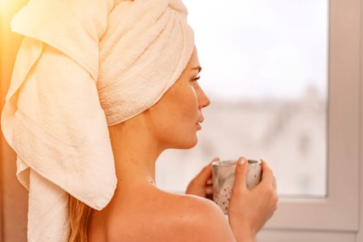 Young serene relaxed woman in spa bath towel drinking hot beverage tea coffee after taking shower bath at home. Beauty treatment, hydration concept